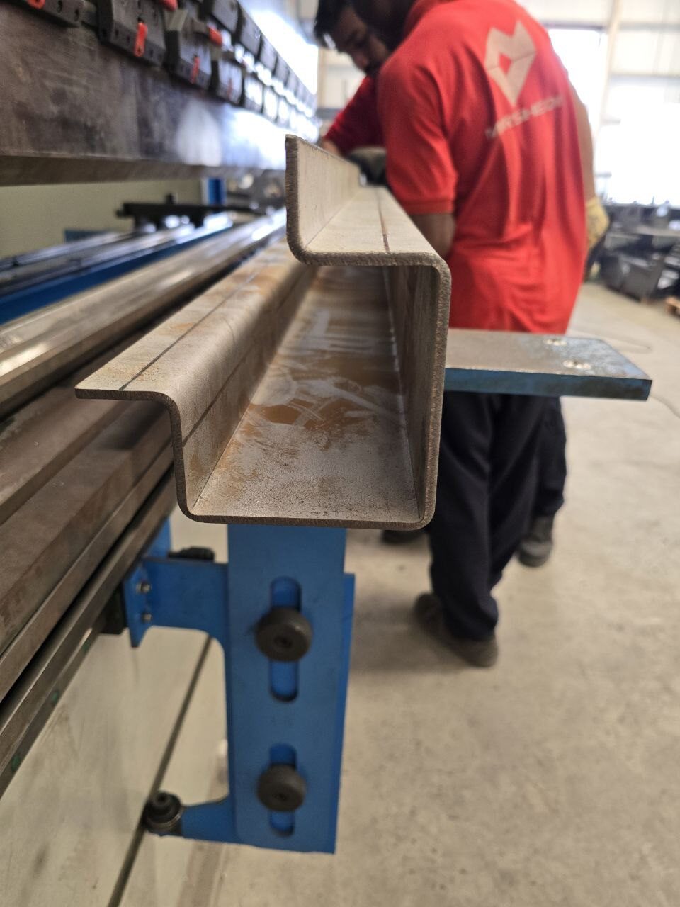 Operator bending a long steel section for enclosures and cladding