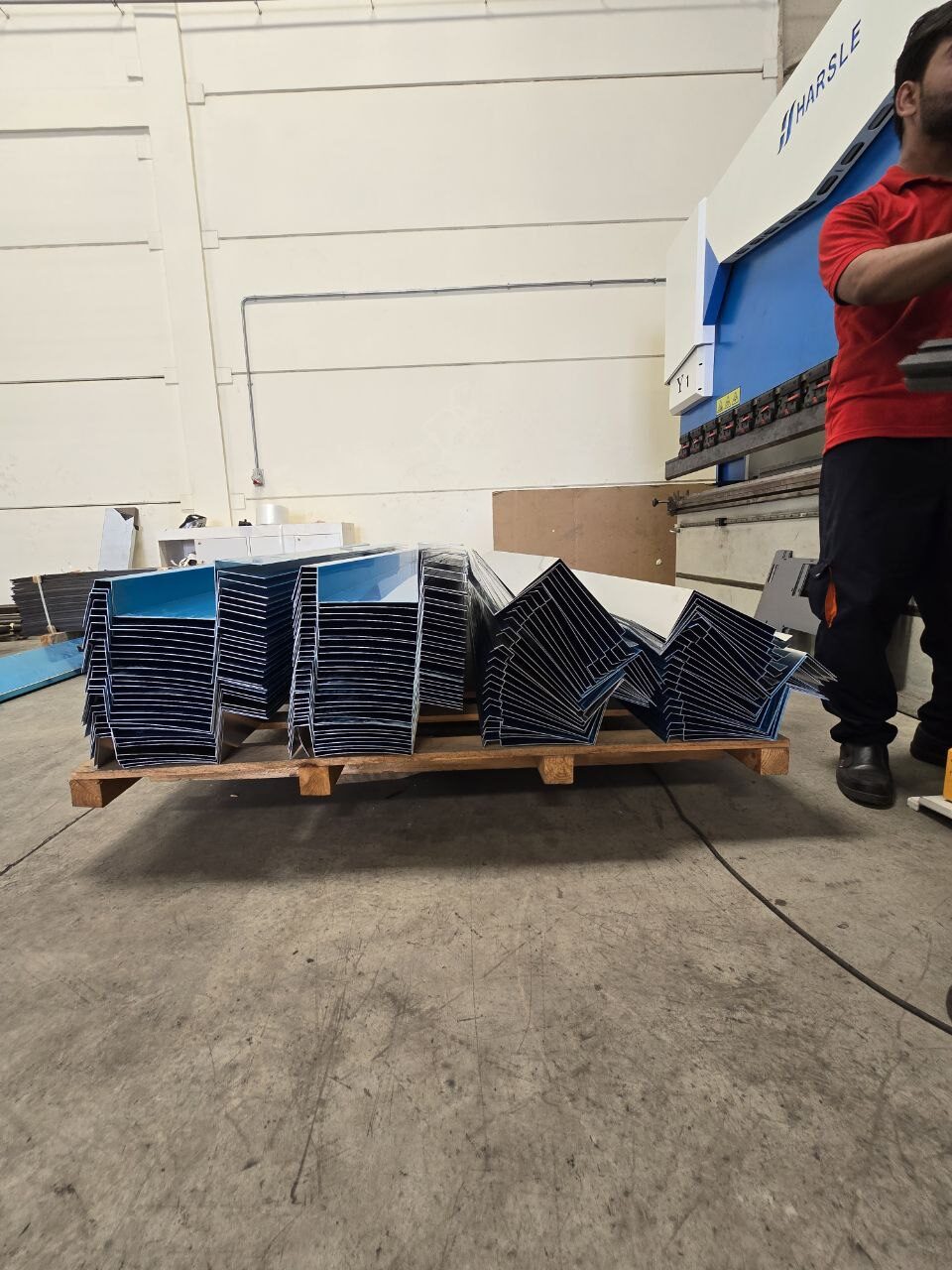 Operator at the press brake with a pallet of bent steel parts